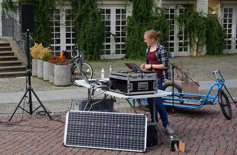 Foto einer Veranstaltung, wo wir vor unserem Tisch eine Solarplatte stehen haben, um unsere Akkus zu laden.